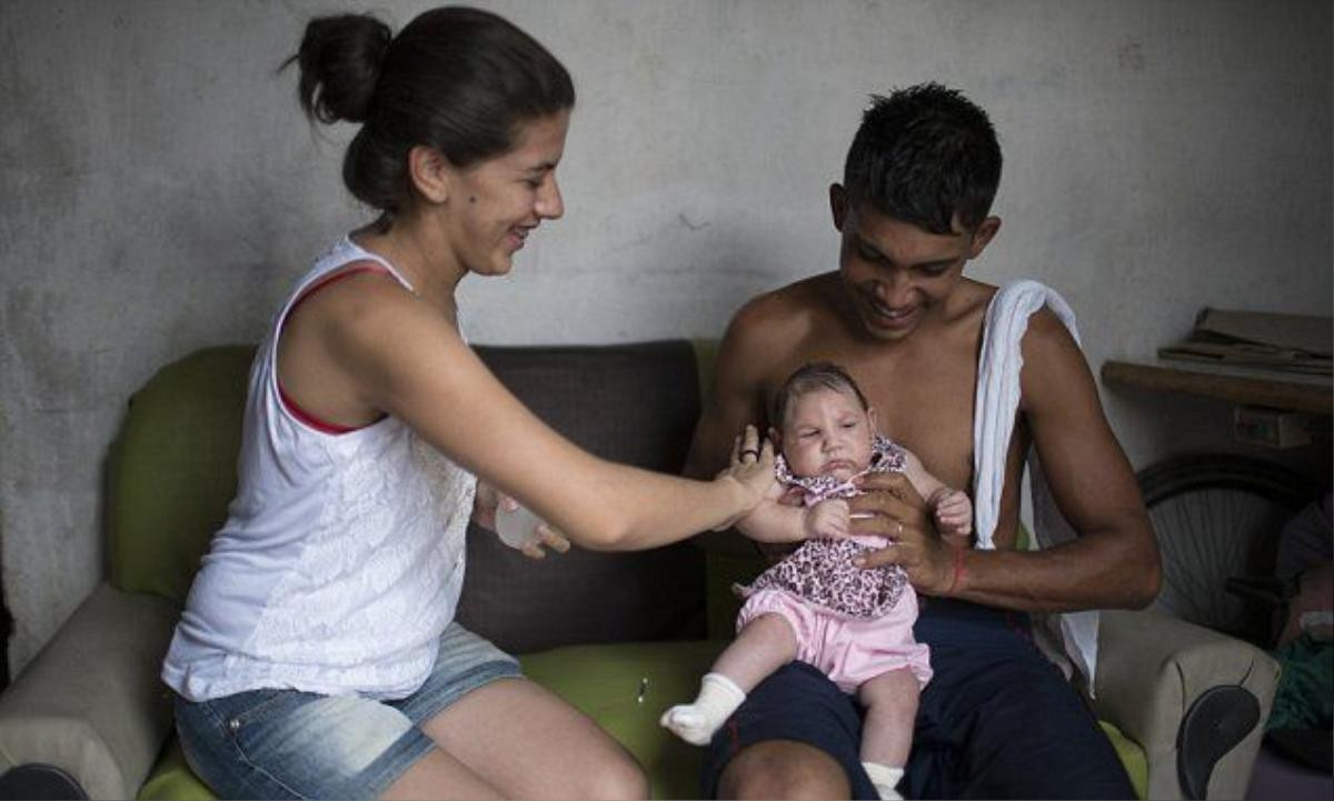 In this Dec. 22, 2015 photo, Angelica Pereira applies perfume on Luiza as her father Dejailson Arruda holds her at their house in Santa Cruz do Capibaribe, Pernambuco state, Brazil. While theres never before been a detected link between the virus and microcephaly, there has never been an epidemic of Zika in the proportions that we are looking at now in Brazil, said Pedro Fernando Vasconcelos, a researcher at Evandro Chagas Institute investigating an association between the virus and the birth defects. (AP Photo/Felipe Dana)